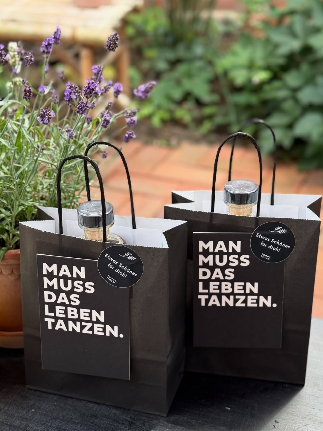 Schwarze Papiertaschen mit Postkarte mit der Aufschrift: Man muss das Leben tanzen,.