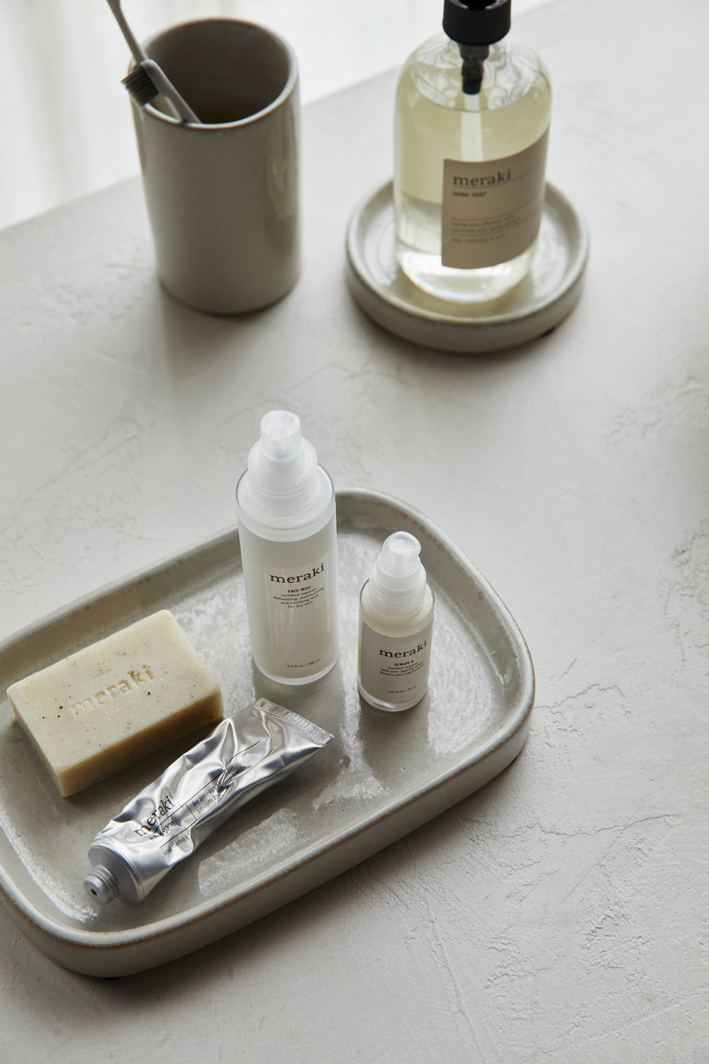 Seifen und Cremes von dem Label Meraki liegen auf einem Keramiktablett.